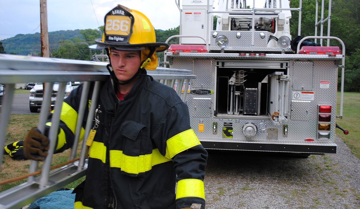 Volunteer firefighter carrying ladder