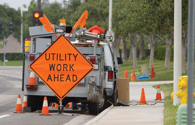 Utility Work Ahead orange sign behind truck on street